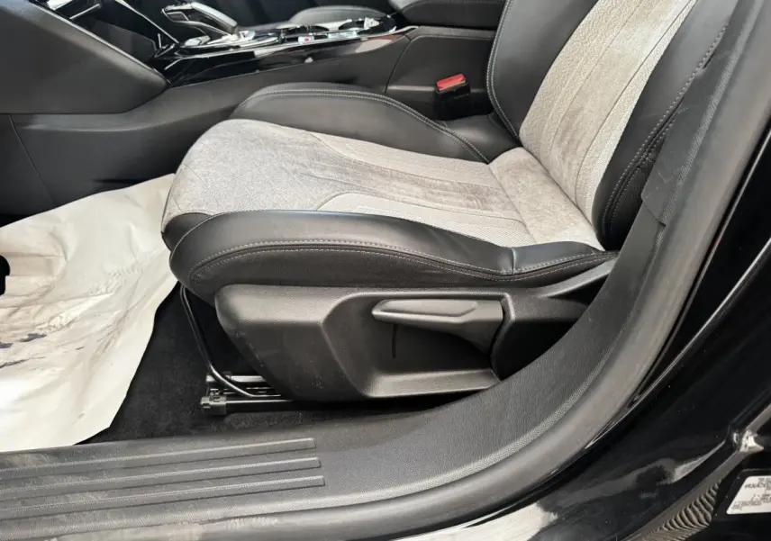 Vue rapprochée du siège avant droit gris et noir du Peugeot E-2008 électrique GT Pack noir, avec console centrale visible.