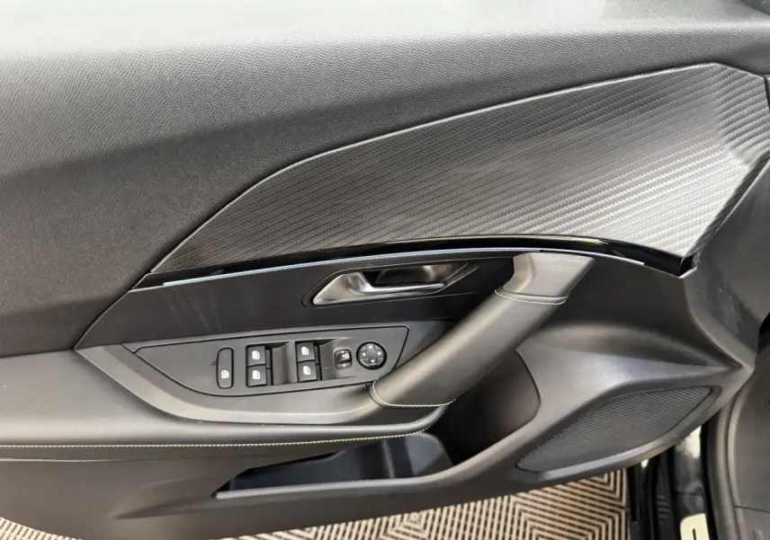 Vue intérieure côté gauche de la porte PEUGEOT E-2008 GT Pack noire avec commandes vitres et insert effet carbone.