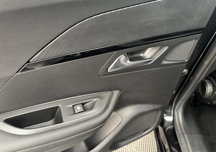 Gros plan sur la porte intérieure côté gauche noire du Peugeot E-2008 électrique GT Pack avec poignée et bouton de verrouillage.