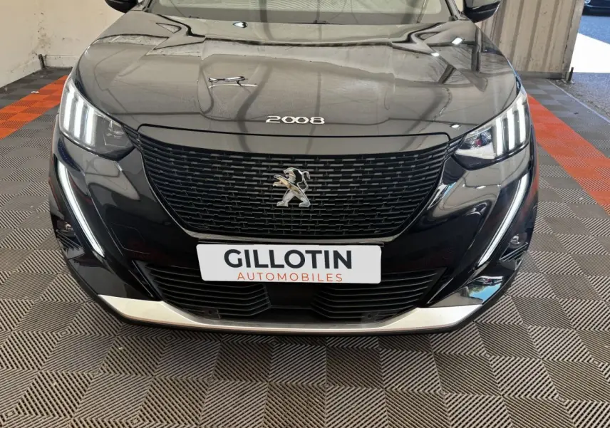 Vue frontale d’un Peugeot E-2008 électrique GT Pack noir, avec calandre noire et feux LED distinctifs allumés.