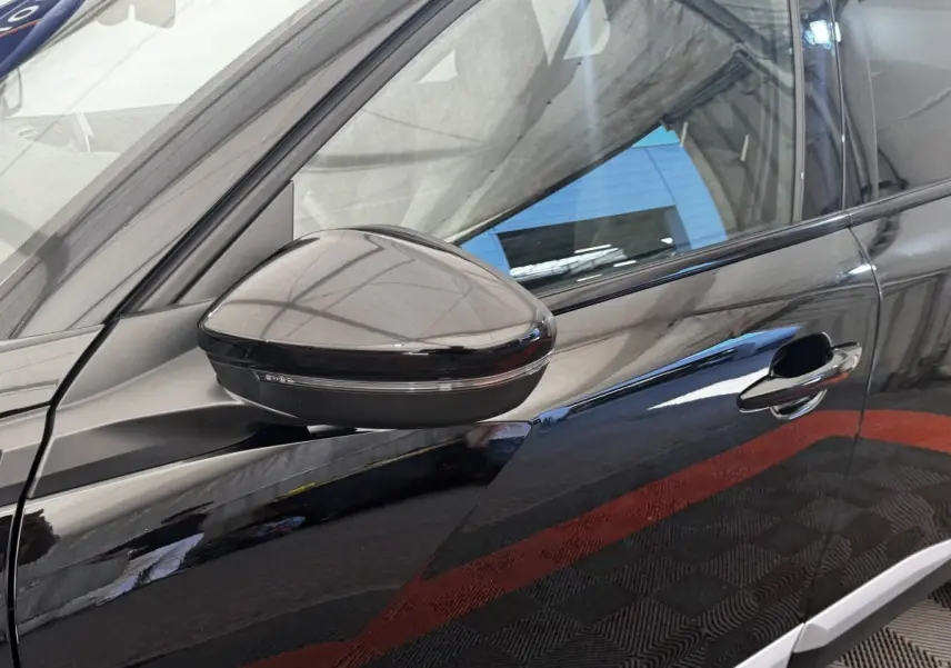 Gros plan sur le rétroviseur côté gauche et la porte noire brillante du Peugeot E-2008 électrique GT Pack.