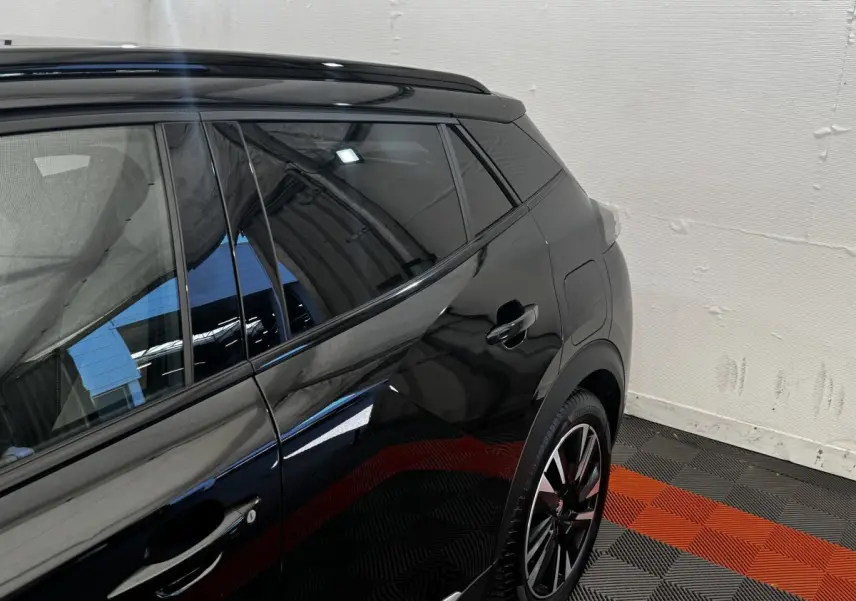 Vue latérale arrière droite du Peugeot E-2008 GT Pack électrique noir, avec jante alliage et vitres teintées.