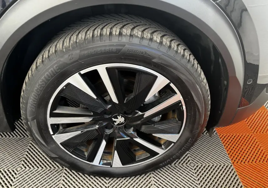 Gros plan sur la roue avant droite noire et argentée du Peugeot E-2008 électrique GT Pack 2021.