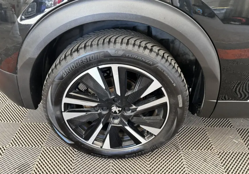 Gros plan sur la roue avant droite noire avec jante alliage bicolore du Peugeot E-2008 Electrique GT Pack 2021.
