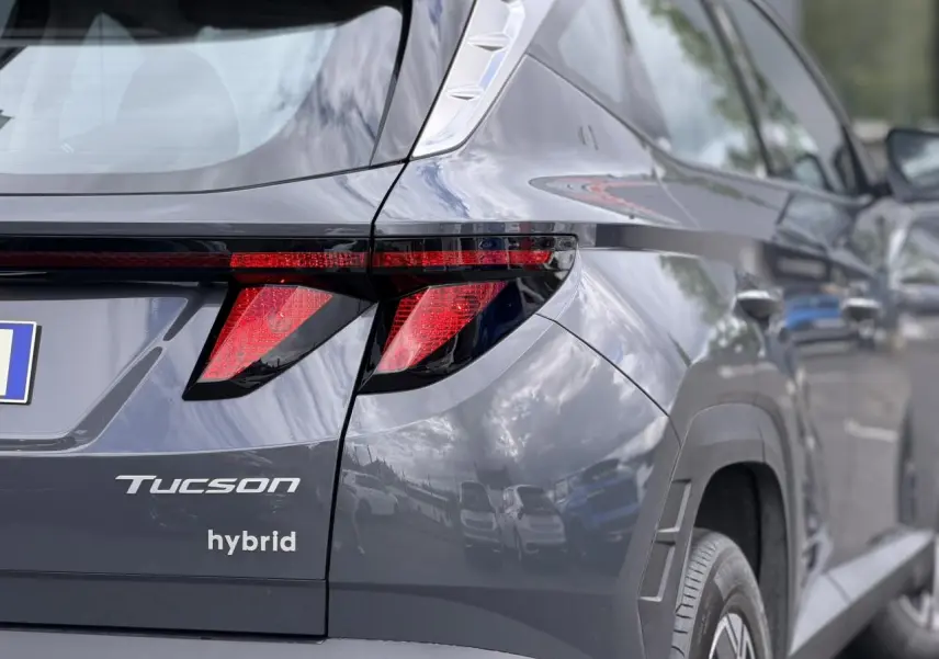 Vue 3/4 arrière droite du Hyundai Tucson Ecotronic Gray avec feux arrière LED et logo hybrid visible.