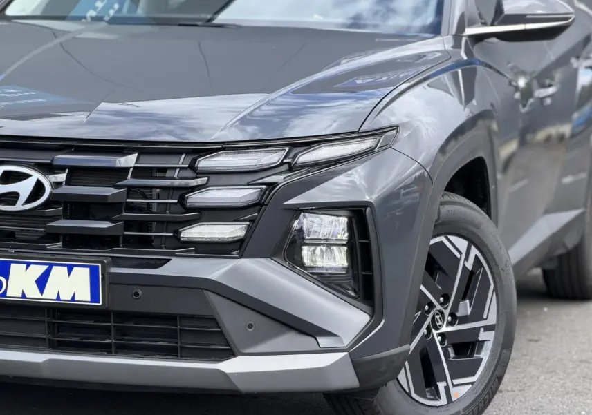 Gros plan sur l’avant droit du Hyundai Tucson Ecotronic Gray 2026, mettant en valeur ses phares bi-LED et jantes alliage 17 pouces.