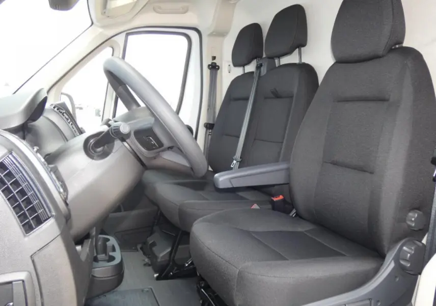 Vue intérieure côté conducteur du Citroën Jumper 2025, sièges noirs et volant en cuir visible.