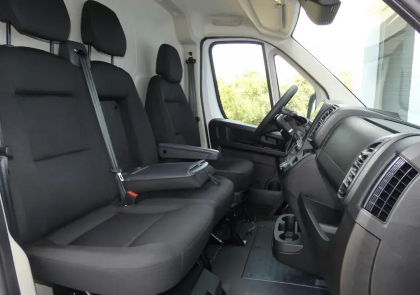 Vue intérieure côté conducteur du Citroën Jumper 2025 blanc, montrant les sièges noirs et le tableau de bord moderne.