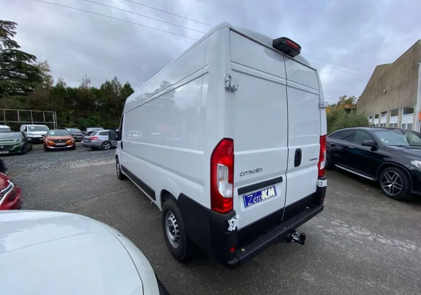 Vue 3/4 arrière droite d’un utilitaire Citroën Jumper blanc avec porte arrière ouverte et crochet d’attelage visible.