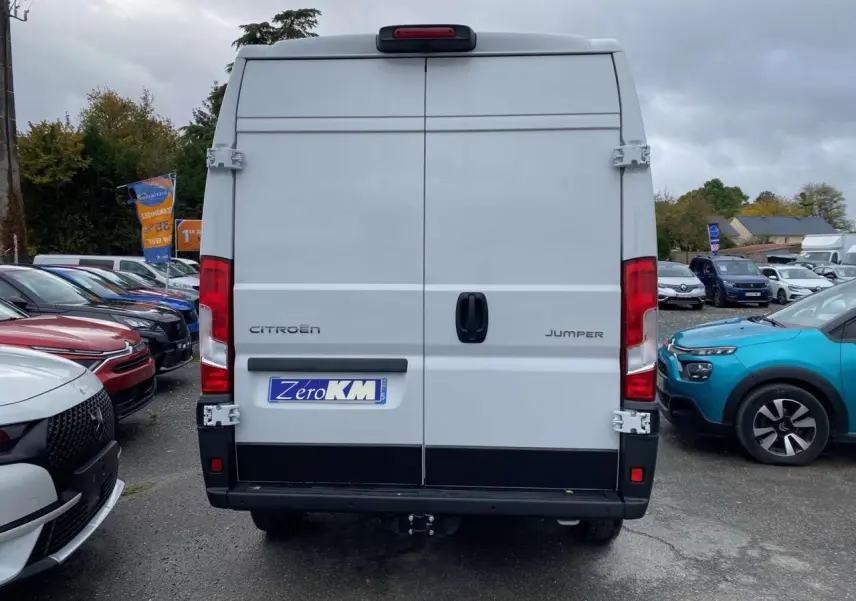Vue arrière d'un utilitaire Citroën Jumper blanc 2025 avec portes battantes et crochet d'attelage visible.