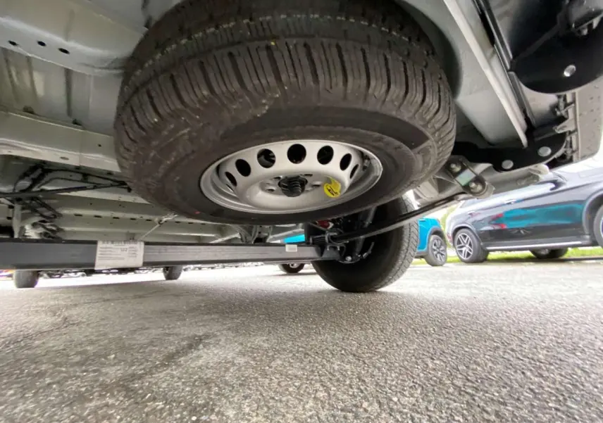 Vue en contre-plongée sous un Citroën Jumper blanc 2025, montrant la roue de secours sous le châssis arrière.