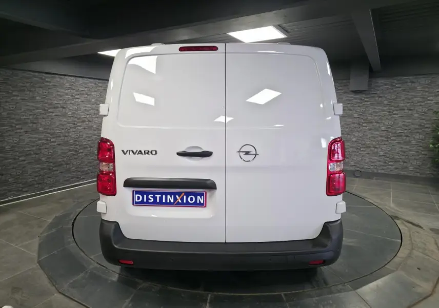 Vue arrière d’un Opel Vivaro blanc avec portes battantes et logo distinctif sur fond intérieur gris.