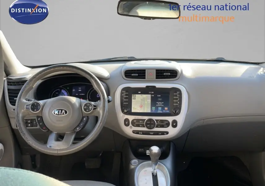Vue intérieure frontale du tableau de bord et volant gris clair de la Kia Soul EV 2016 avec écran tactile central et levier de boîte automatique.