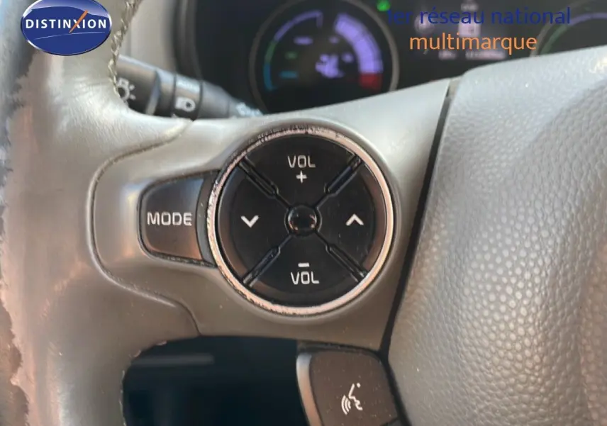 Gros plan sur les commandes de volume et mode au volant gris d'une KIA Soul EV électrique noir Shadow Metal avec toit rouge.