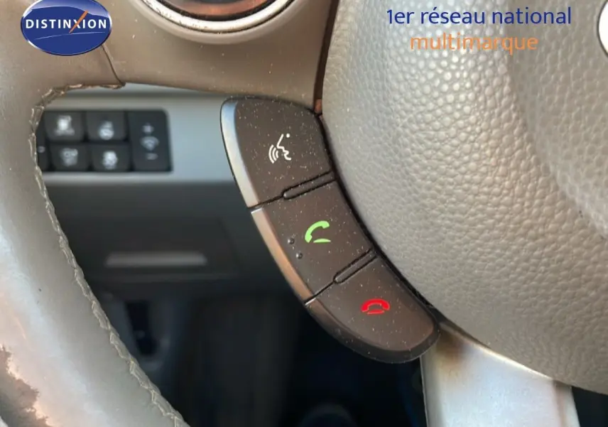 Gros plan sur les commandes téléphoniques au volant en cuir gris d'une KIA Soul EV 2016, intérieur visible en arrière-plan.