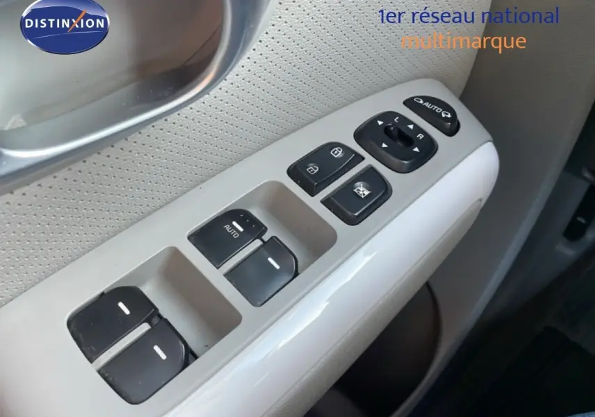 Gros plan sur les commandes des vitres et rétroviseurs côté conducteur d’une Kia Soul EV 2016 avec intérieur gris clair.