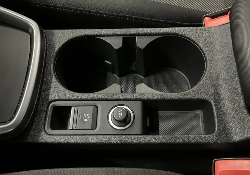 Gros plan sur la console centrale noire de l'Audi A3 Sportback 2021, avec porte-gobelets et prise 12V visible.