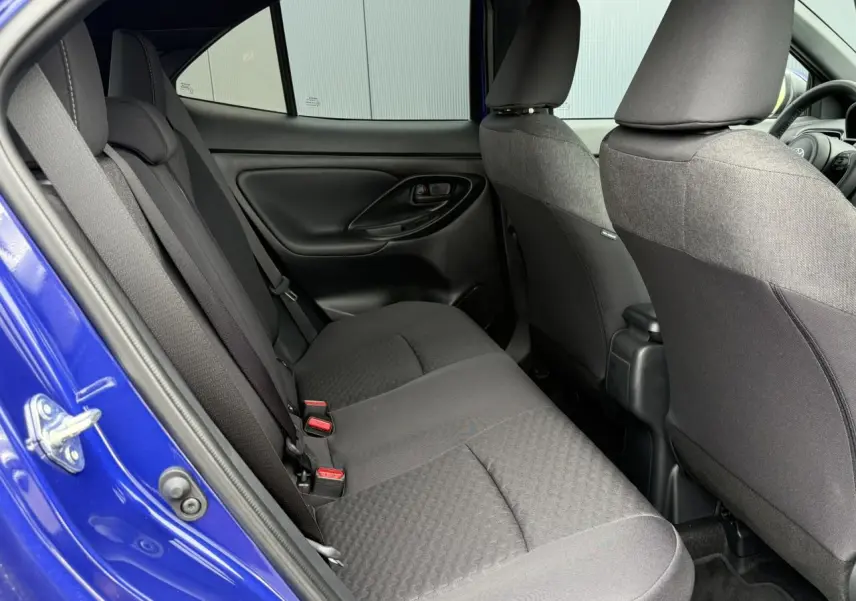 Vue intérieure côté gauche des sièges arrière noirs d'une Toyota Yaris Cross 1.5 Hybrid 116 Design bleu Genievre.