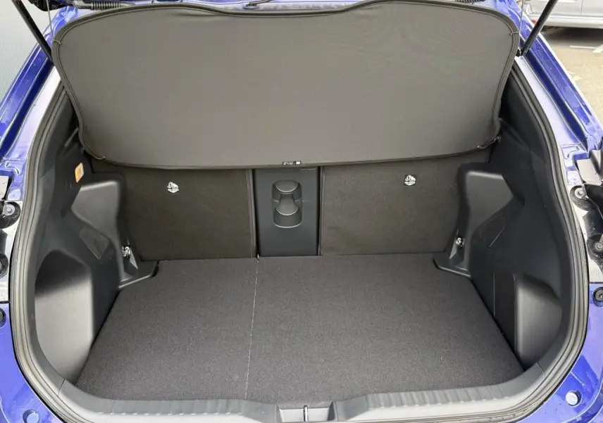 Vue arrière du coffre ouvert du Toyota Yaris Cross bleu Genievre, montrant un plancher plat et une tablette de séparation.