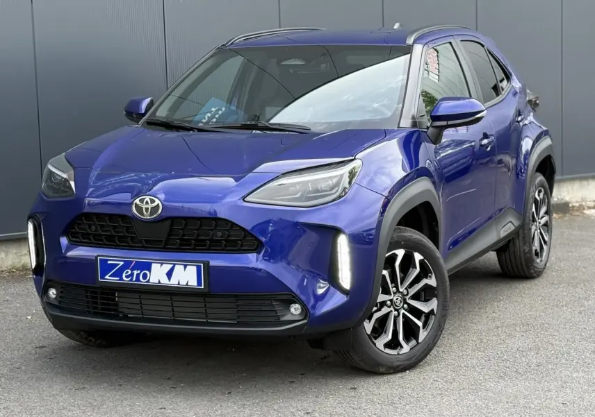 Toyota Yaris Cross bleu Genievre vue 3/4 avant droit avec feux LED verticaux allumés et jantes alliage noires.