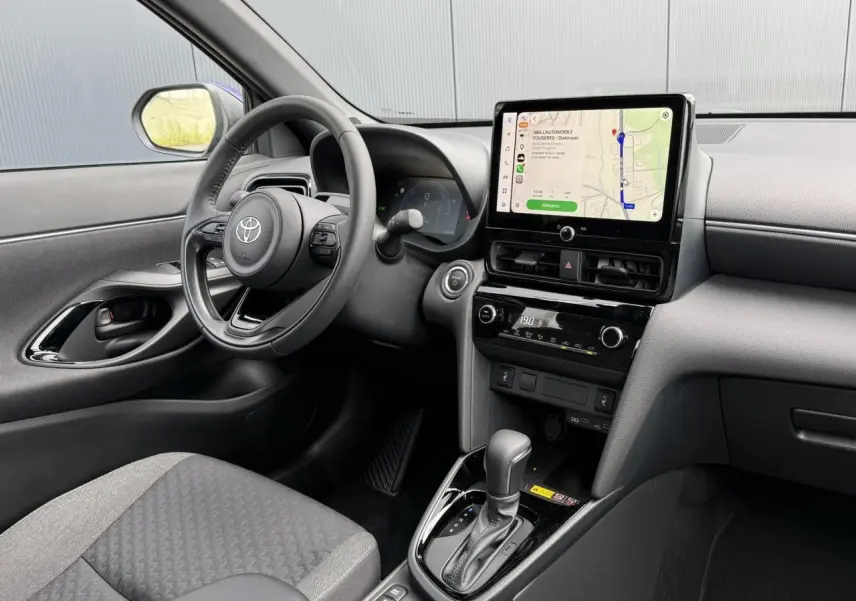 Intérieur de la Toyota Yaris Cross 1.5 Hybrid 116 Design 2026, vue côté conducteur sur le tableau de bord et écran tactile.