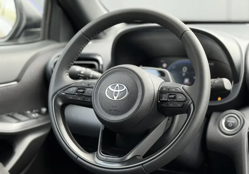 Vue rapprochée du volant cuir noir de la Toyota Yaris Cross 2026, avec commandes intégrées et bouton démarrage.