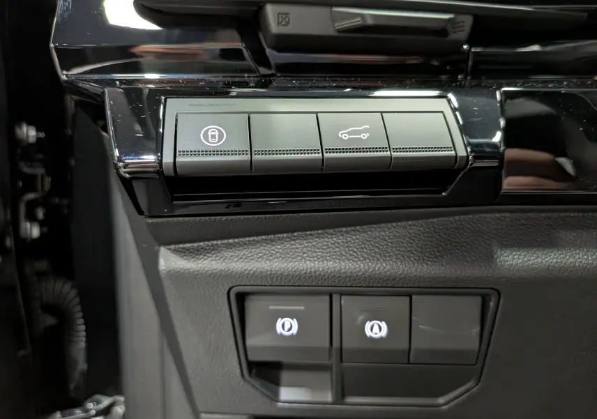 Gros plan sur les boutons de commande noirs du tableau de bord du Renault Austral noir, avec icônes éclairées.
