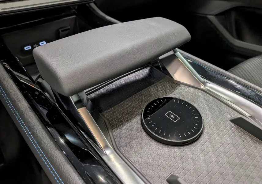 Détail intérieur du Renault Austral full hybrid, montrant le chargeur sans fil et l'accoudoir en cuir gris.