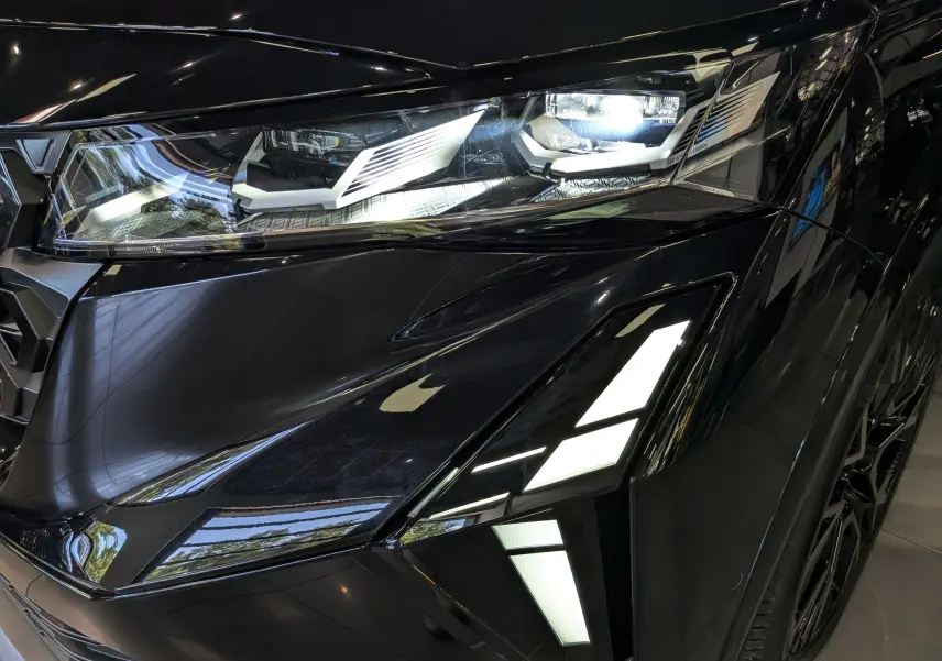 Gros plan sur le phare avant droit noir brillant du Renault Austral full hybrid Esprit Alpine 2026 avec éclairage LED distinctif.