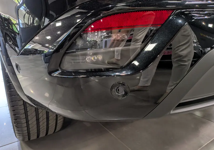 Gros plan sur le feu arrière droit noir brillant du Renault Austral full hybrid 2026 avec reflet de l'environnement intérieur.