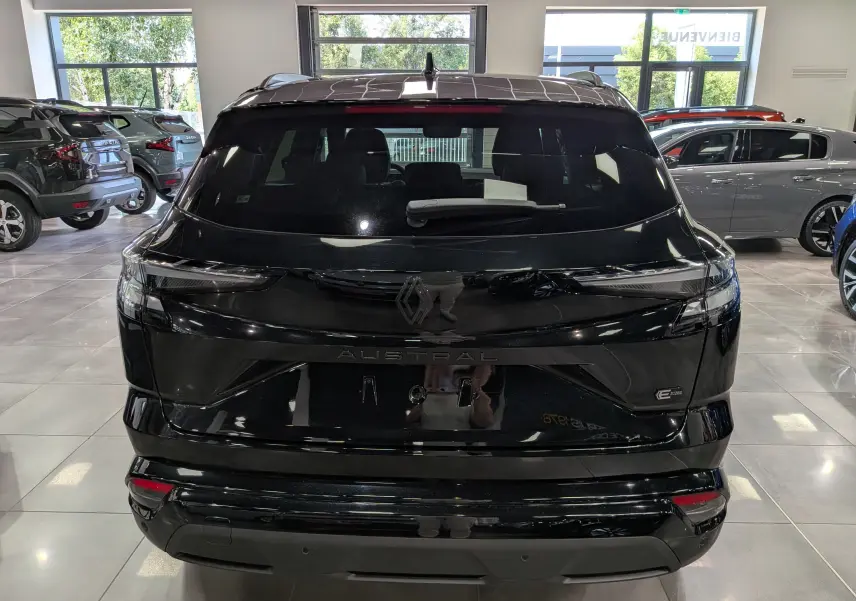 Vue arrière d’un Renault Austral noir full hybrid E-Tech 200 ch Esprit Alpine en showroom, avec feux LED fins et logo central.