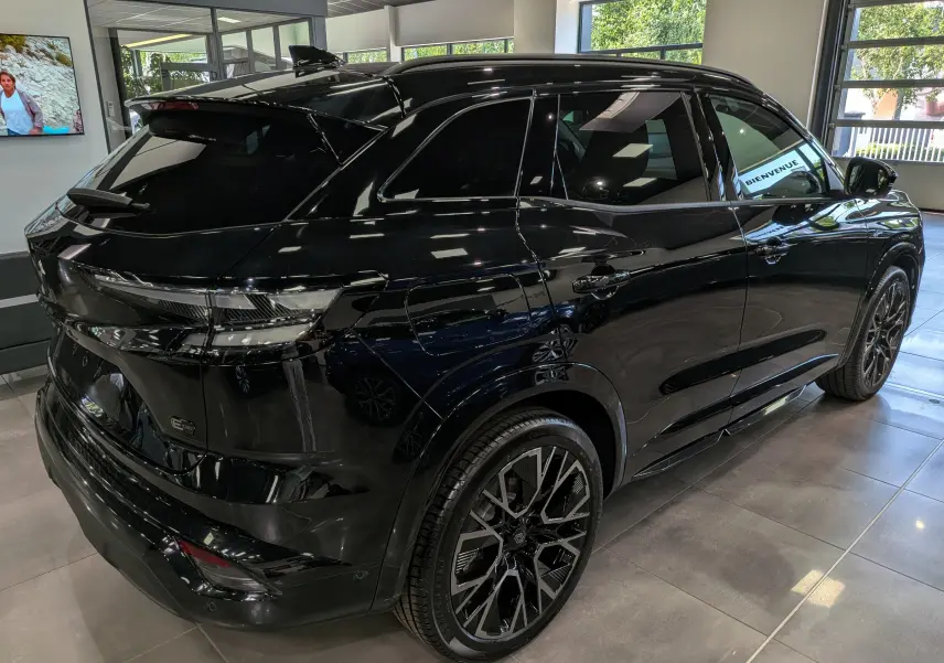Renault Austral noir en 3/4 arrière droit, soulignant ses jantes noires et son design moderne en showroom.