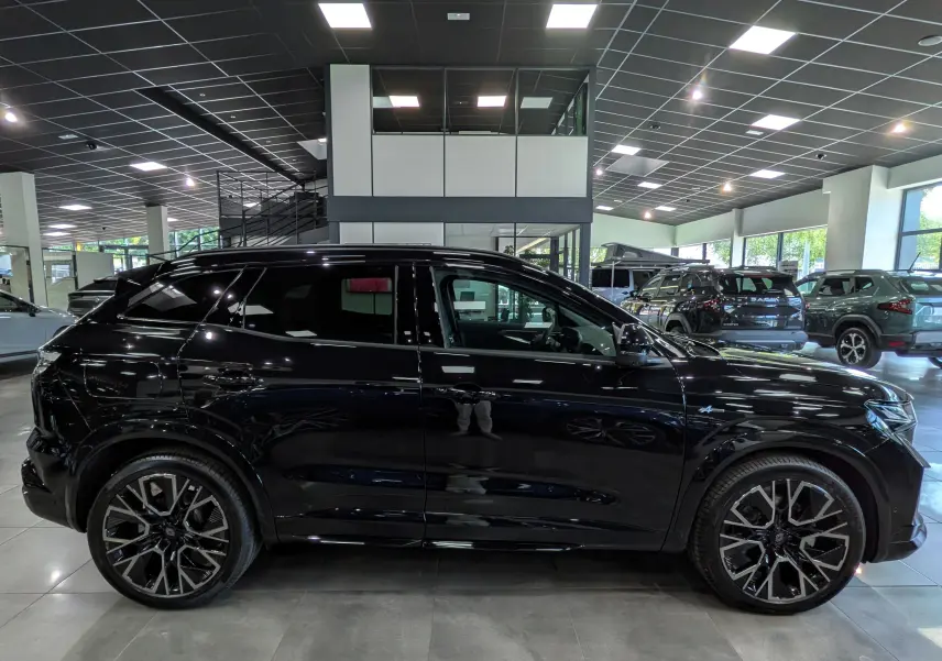 Profil côté gauche d'un Renault Austral noir full hybrid E-Tech 200 ch Esprit Alpine en showroom, avec jantes bi-ton distinctives.