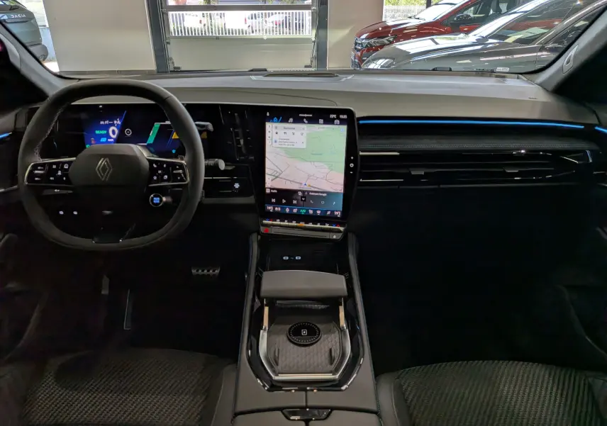Vue intérieure frontale du tableau de bord noir du Renault Austral full hybrid avec écran tactile central vertical et volant multifonction.