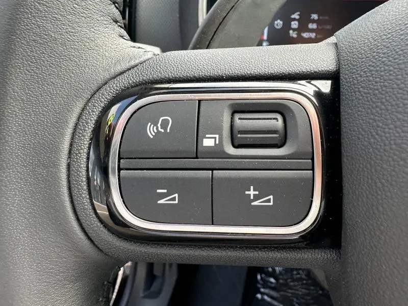 Gros plan sur les commandes noires du volant du Citroën C5 Aircross 2025, avec finition chromée autour des boutons.