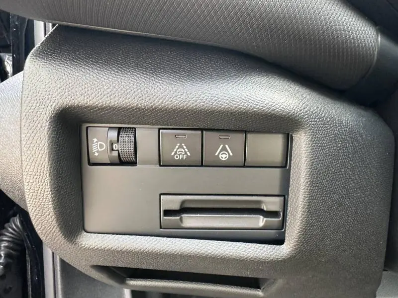 Gros plan sur les commandes de réglage des phares et d’aide à la conduite du tableau de bord du Citroën C5 Aircross noir.