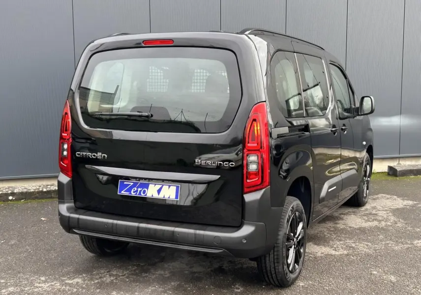 Vue 3/4 arrière droite d'un Citroën Berlingo Multispace noir Perla avec jantes alliage noires et feux arrière allumés.