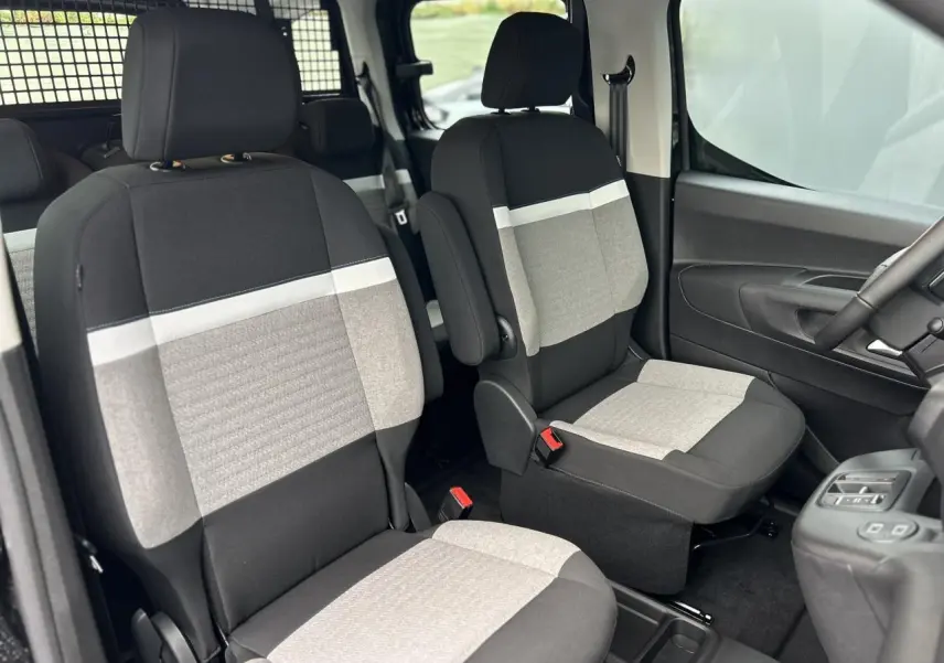 Vue intérieure avant du Citroën Berlingo Multispace 2025, sièges tissu bicolore gris et noir avec accoudoirs.