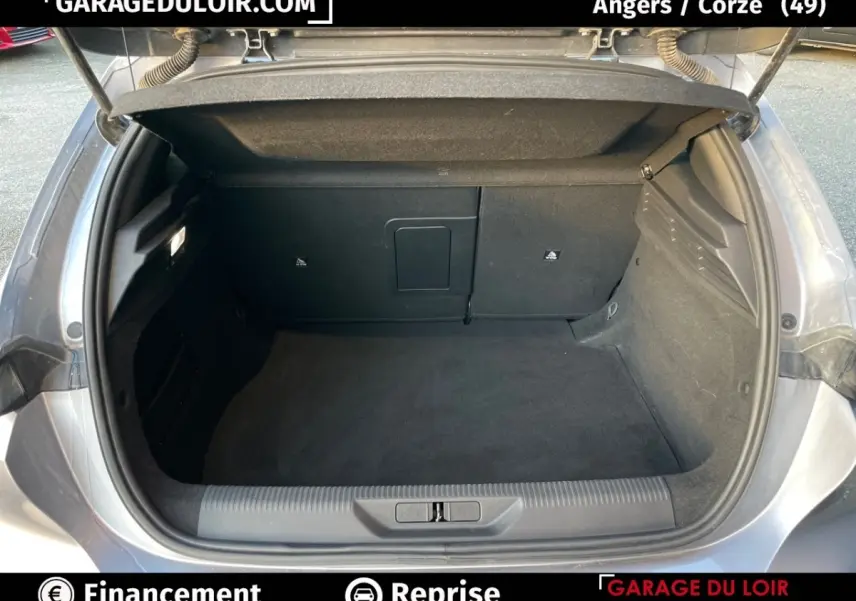 Coffre ouvert d'une Peugeot 308 gris foncé, vue arrière montrant l'espace de chargement propre et spacieux.