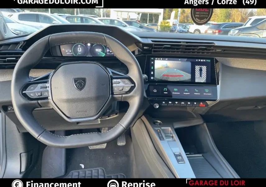 Vue intérieure centrée sur le volant et la console centrale d’une Peugeot 308 gris foncé avec écran tactile et tableau de bord numérique.