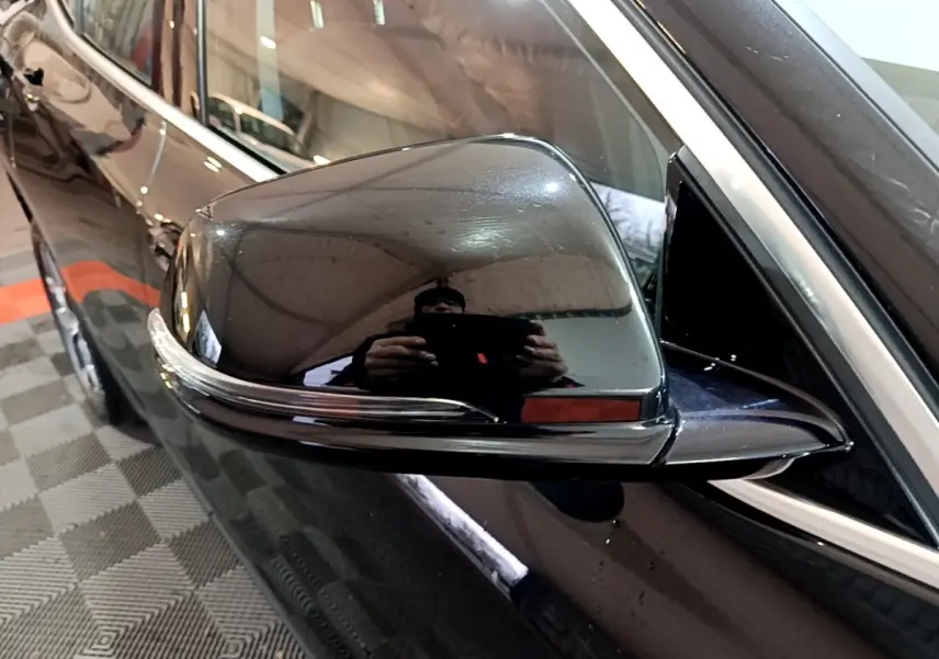 Gros plan sur le rétroviseur côté conducteur noir brillant d’un BMW X2 sDrive18i Lounge 2023.