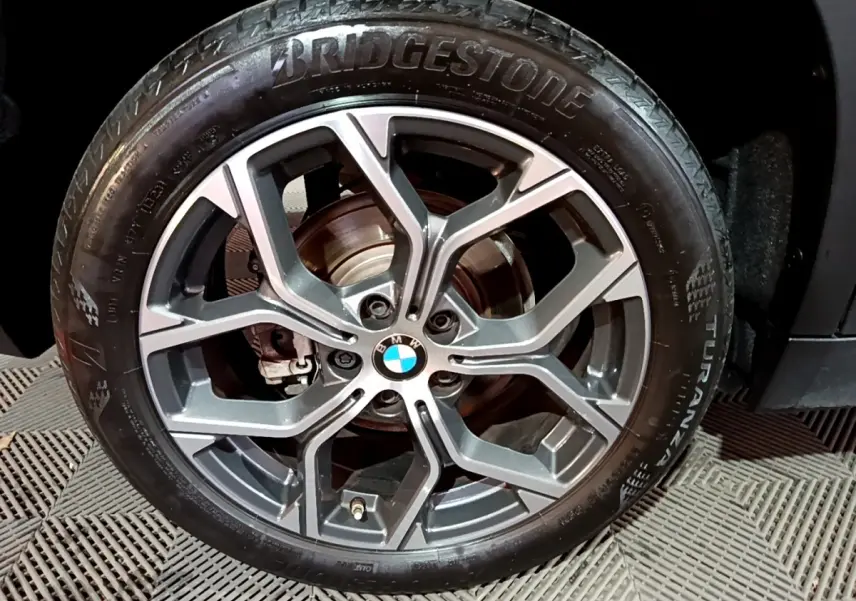 Gros plan sur la roue avant droite noire d’une BMW X2 2023 avec jante alliage gris foncé et pneu Bridgestone.