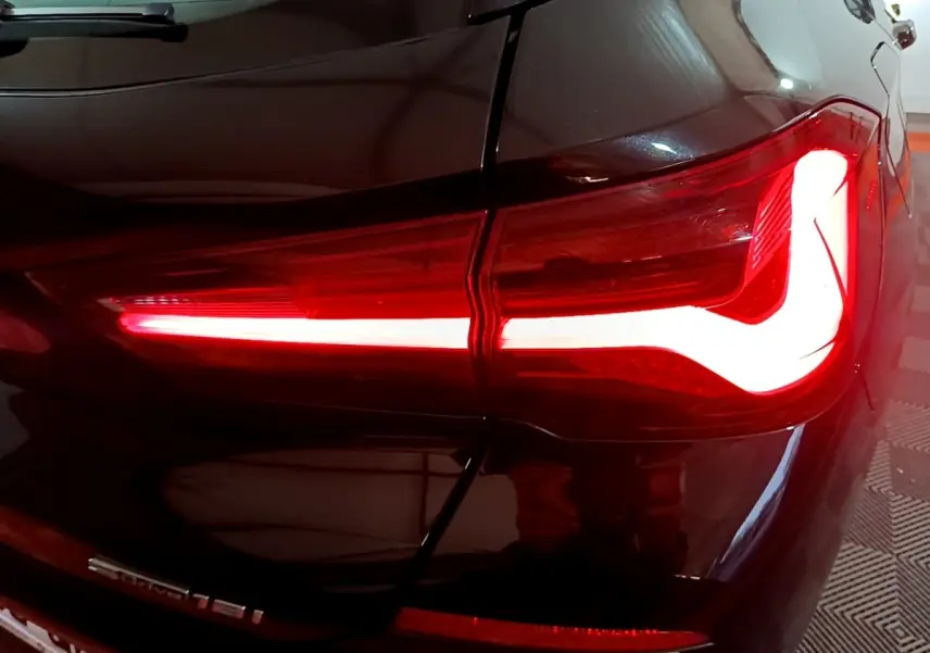 Gros plan sur le feu arrière droit allumé d’un BMW X2 sDrive18i Lounge noir, soulignant la ligne lumineuse distinctive.