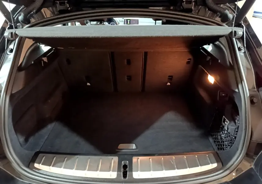 Coffre ouvert noir du BMW X2 sDrive18i Lounge 2023, montrant l’espace de chargement avec éclairage intérieur.