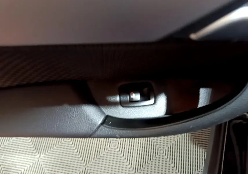Détail du bouton de verrouillage sur la porte intérieure noire d'une BMW X2 sDrive18i Lounge 2023.