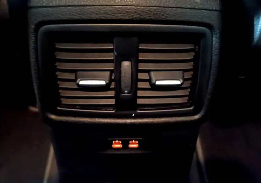 Gros plan sur les aérateurs arrière noirs et les ports USB éclairés en orange du BMW X2 sDrive18i Lounge 2023.