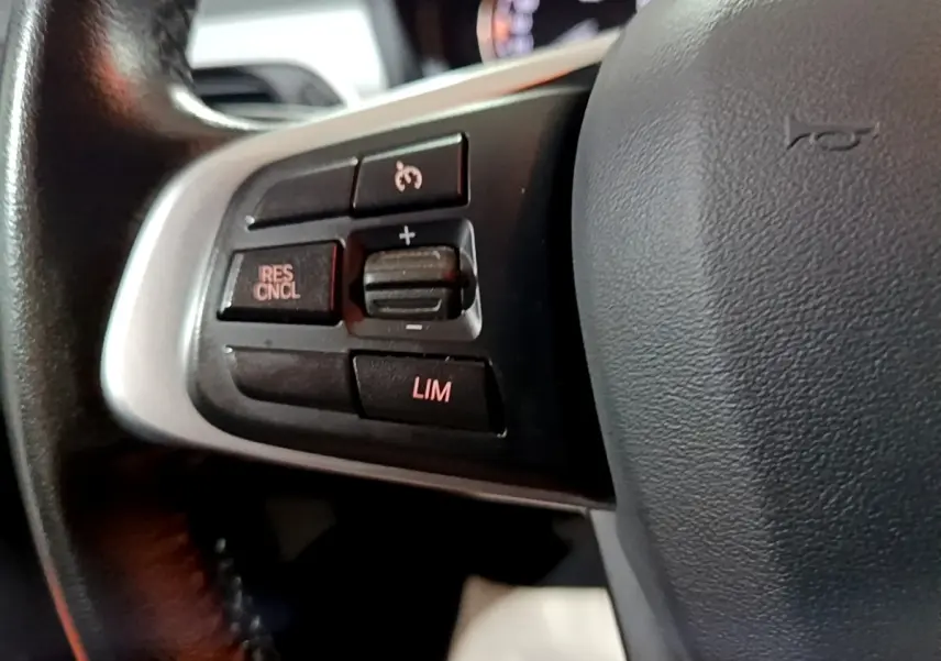 Gros plan sur les commandes de régulateur de vitesse au volant cuir noir de la BMW X2 sDrive18i Lounge 2023.