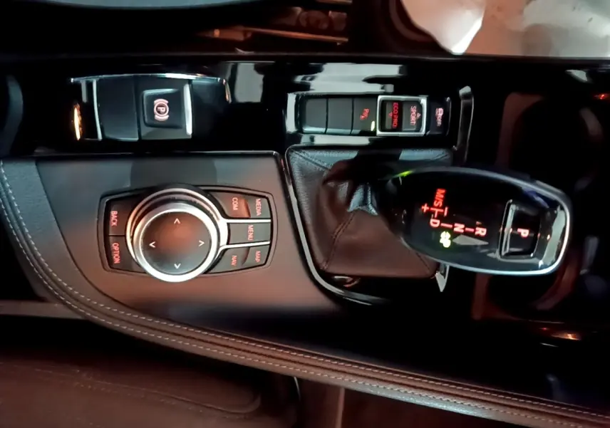 Vue rapprochée de la console centrale noire du BMW X2 2023 avec levier de vitesses automatique et molette de commande.