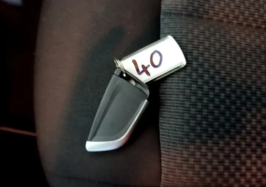 Clé de démarrage BMW posée sur un siège tissu noir à motif, avec étiquette numérotée 40 visible.