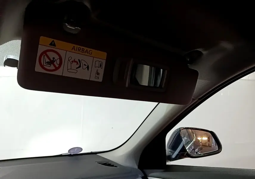 Vue intérieure côté conducteur du BMW X2 noir 2023, avec pare-soleil baissé et rétroviseur extérieur visible.